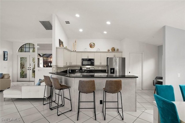 kitchen featuring white cabinets, a kitchen breakfast bar, vaulted ceiling, kitchen peninsula, and stainless steel appliances