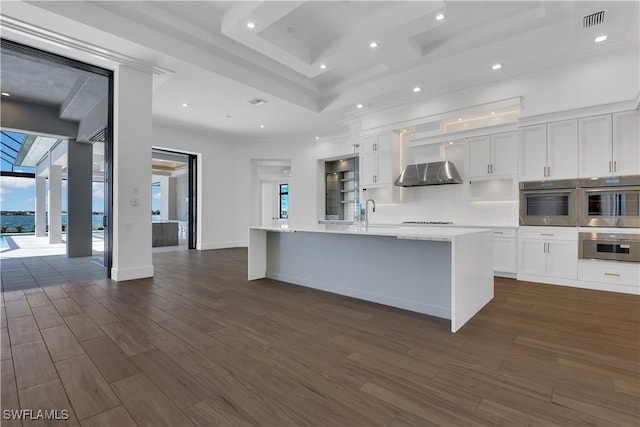 kitchen with a large island, white cabinetry, and range hood