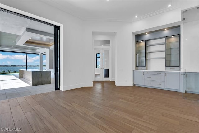 unfurnished living room featuring crown molding and a water view