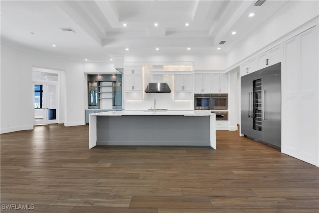 kitchen with dark wood-type flooring, white cabinets, stainless steel built in fridge, a spacious island, and sink