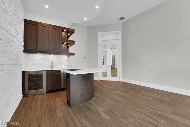 kitchen featuring decorative backsplash, french doors, dark brown cabinetry, dark wood-type flooring, and wine cooler