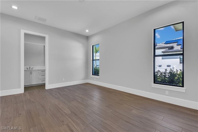 unfurnished bedroom featuring light hardwood / wood-style floors, sink, and connected bathroom