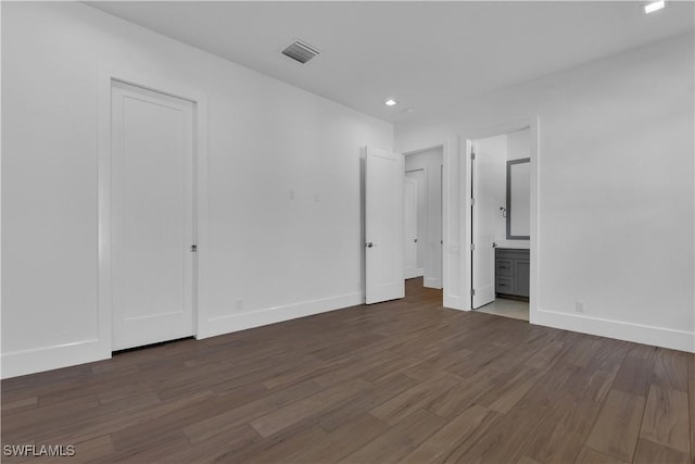 unfurnished bedroom featuring dark wood-type flooring and ensuite bath