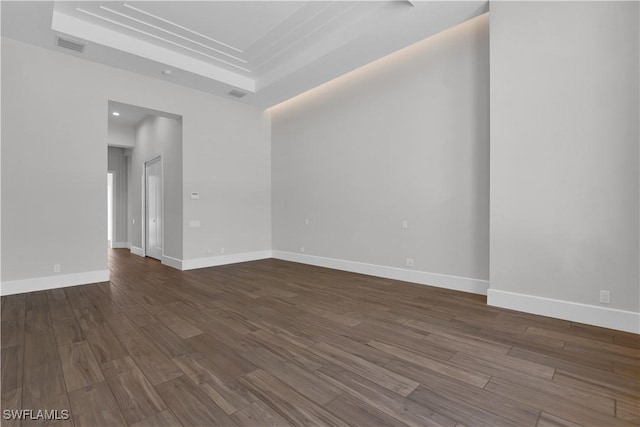 spare room with a raised ceiling and dark hardwood / wood-style floors