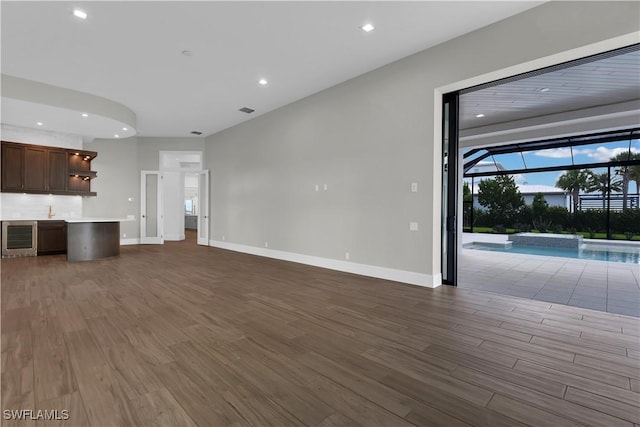 unfurnished living room featuring dark hardwood / wood-style flooring and wine cooler