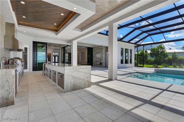 view of swimming pool featuring glass enclosure, a wet bar, exterior kitchen, and a patio