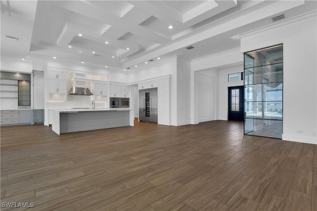 unfurnished living room with a high ceiling, dark hardwood / wood-style flooring, ornamental molding, and sink