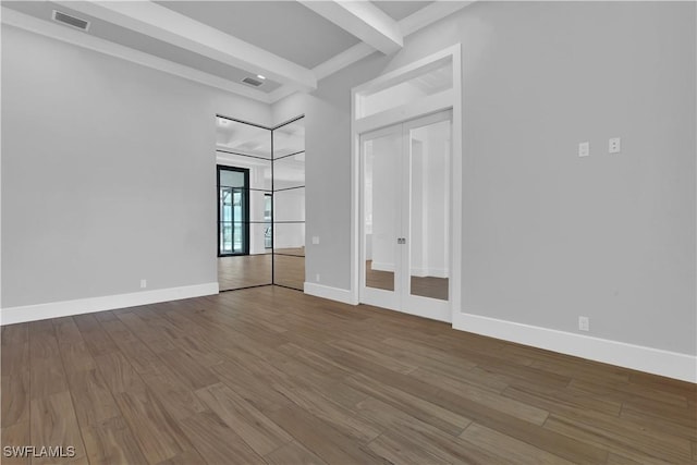 unfurnished room featuring beamed ceiling and hardwood / wood-style flooring