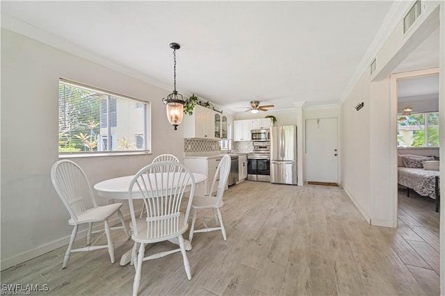 dining space with light hardwood / wood-style flooring, a wealth of natural light, crown molding, and ceiling fan