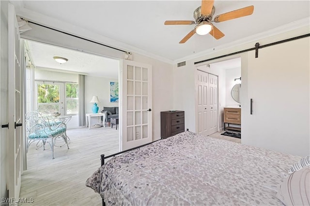 bedroom featuring ceiling fan, french doors, a barn door, crown molding, and a closet