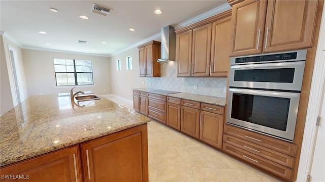 kitchen featuring tasteful backsplash, light stone counters, double oven, sink, and wall chimney range hood