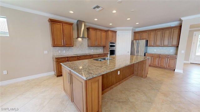 kitchen with appliances with stainless steel finishes, crown molding, sink, wall chimney range hood, and an island with sink