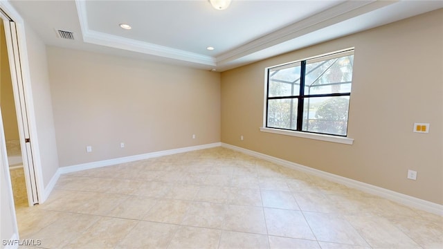 empty room featuring light tile patterned floors, a raised ceiling, and ornamental molding