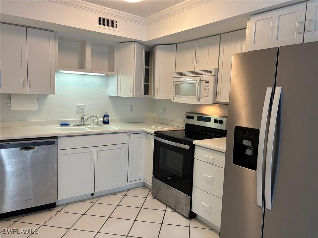 kitchen with white cabinetry, sink, light tile patterned floors, and stainless steel appliances