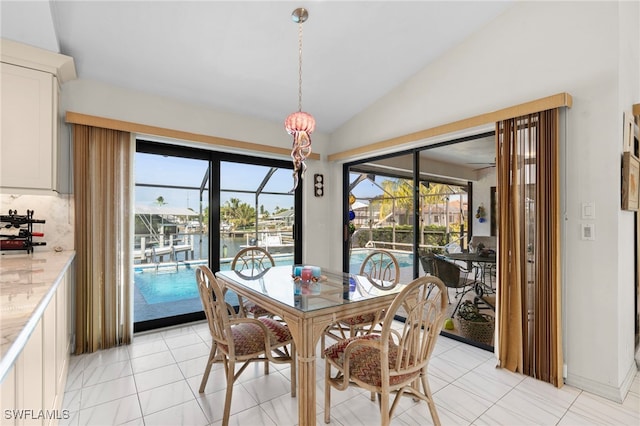 dining room featuring plenty of natural light, light tile patterned flooring, and lofted ceiling