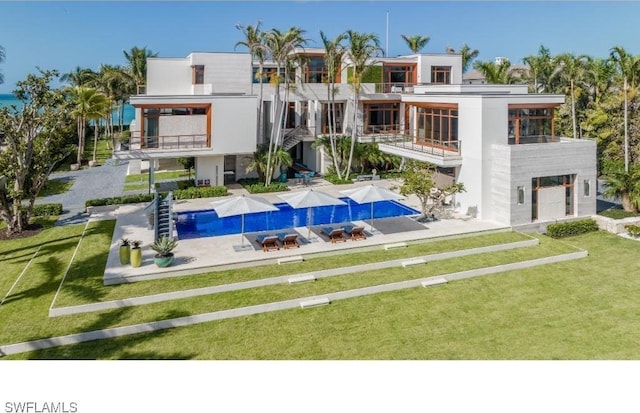 rear view of property featuring a balcony, a yard, and a patio