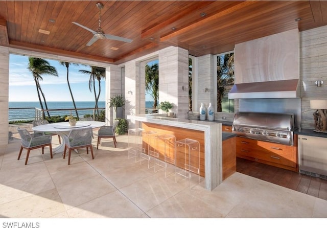 view of patio featuring grilling area, a water view, ceiling fan, area for grilling, and a bar