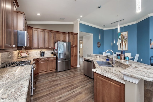 kitchen with sink, a large island with sink, a kitchen bar, decorative backsplash, and appliances with stainless steel finishes