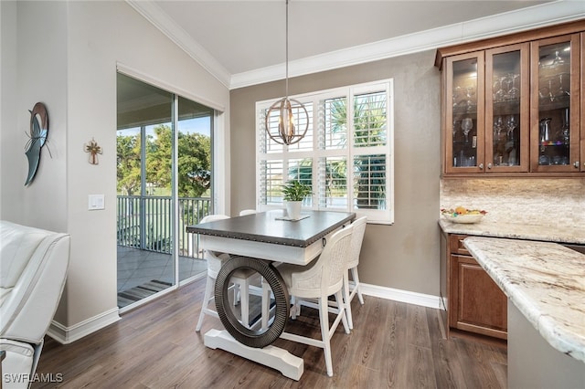 dining area with dark hardwood / wood-style floors, vaulted ceiling, a healthy amount of sunlight, and crown molding