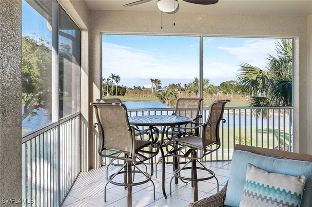 sunroom featuring ceiling fan and a water view