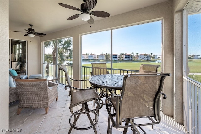 sunroom with a water view, ceiling fan, and a healthy amount of sunlight