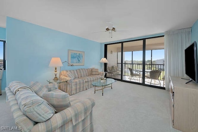 carpeted living room with floor to ceiling windows and ceiling fan