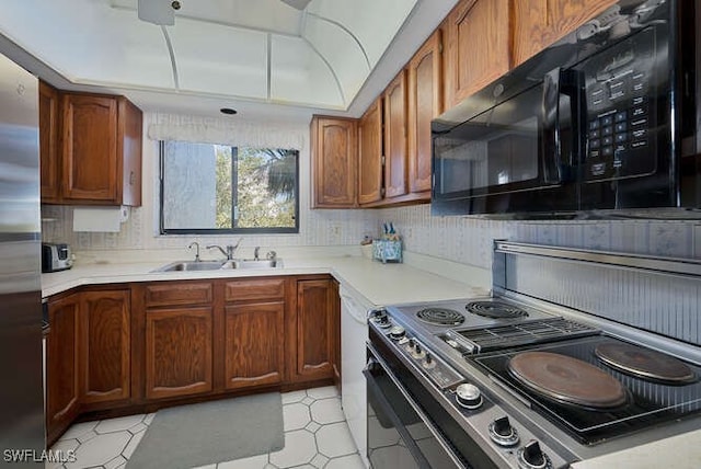 kitchen with sink, stainless steel refrigerator, dishwasher, tasteful backsplash, and range with electric stovetop