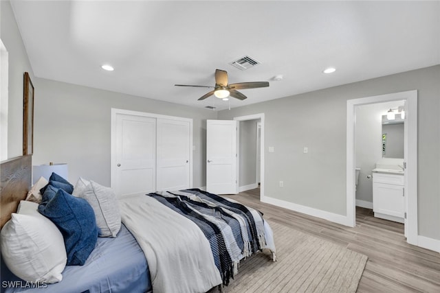 bedroom featuring ceiling fan, light wood-type flooring, ensuite bathroom, and a closet