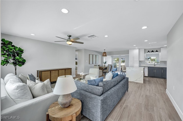 living room featuring ceiling fan, light wood-type flooring, and sink