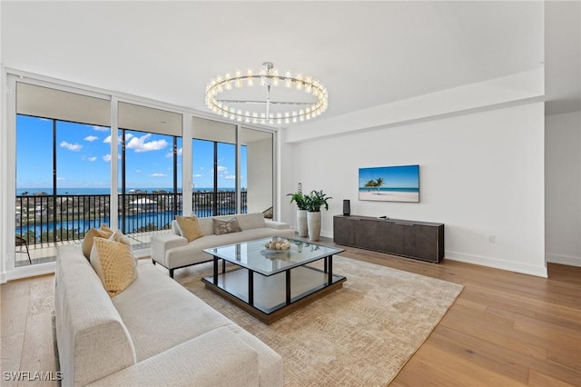 living room with a notable chandelier, wood-type flooring, expansive windows, and a water view