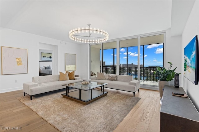 living room featuring an inviting chandelier, expansive windows, and light hardwood / wood-style floors