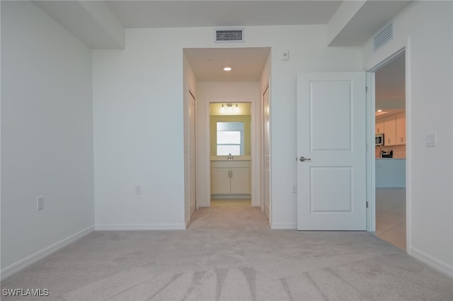 corridor featuring light carpet and sink