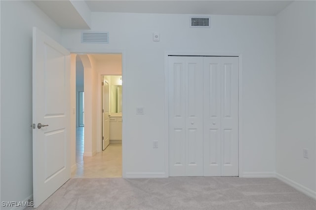 unfurnished bedroom featuring light carpet and a closet