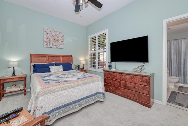 carpeted bedroom with ensuite bath and ceiling fan