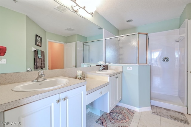 bathroom with tile patterned floors, vanity, a textured ceiling, and walk in shower