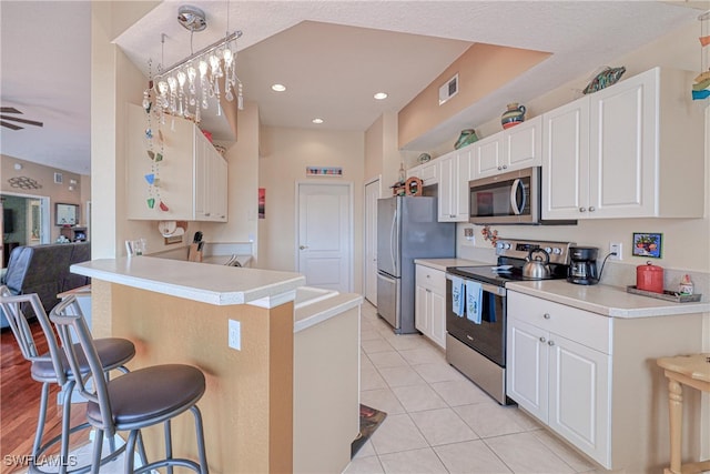 kitchen featuring white cabinetry, a kitchen breakfast bar, kitchen peninsula, pendant lighting, and appliances with stainless steel finishes