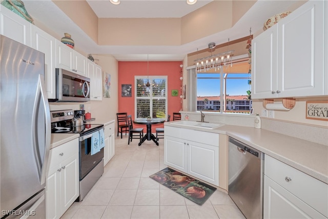 kitchen featuring sink, white cabinets, stainless steel appliances, and decorative light fixtures