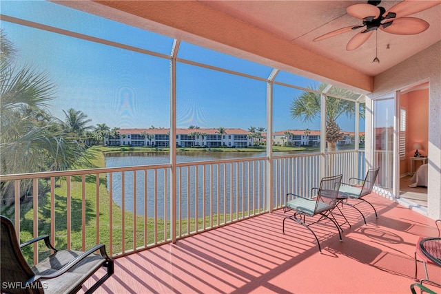 unfurnished sunroom featuring ceiling fan and a water view