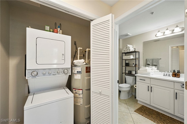 washroom with water heater, stacked washer and dryer, light tile patterned floors, and sink