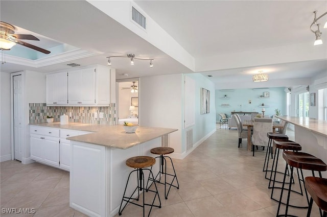 kitchen with a kitchen bar, tasteful backsplash, white cabinetry, and ceiling fan