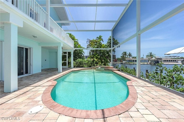 view of pool with glass enclosure, a patio area, and a water view