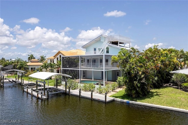 view of dock with a water view, a yard, and a balcony