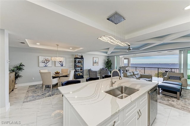 kitchen featuring a tray ceiling, sink, pendant lighting, a center island with sink, and dishwasher