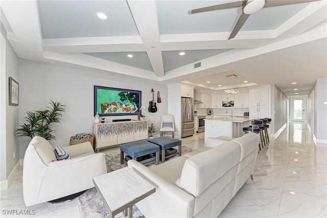 living room with ceiling fan, sink, a tray ceiling, and coffered ceiling