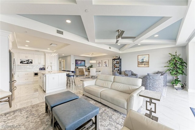 living room with ceiling fan, sink, beamed ceiling, and coffered ceiling