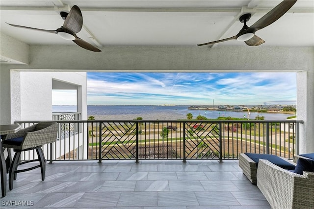 balcony featuring a water view and ceiling fan