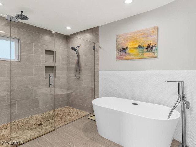 bathroom with shower with separate bathtub and tile walls