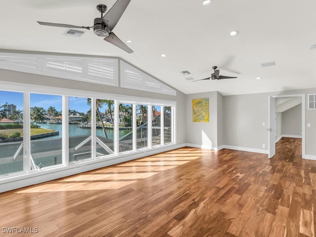 unfurnished living room featuring hardwood / wood-style flooring, ceiling fan, a water view, and vaulted ceiling