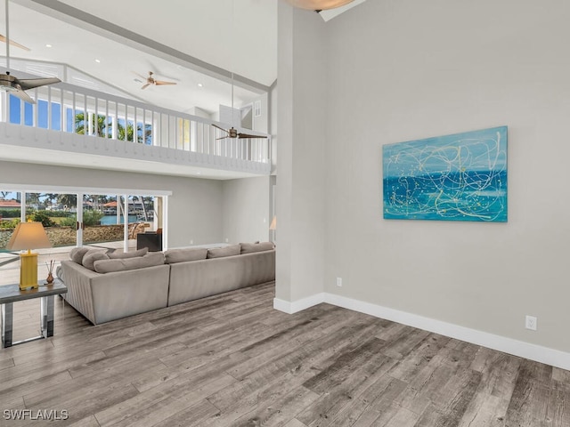 living room with hardwood / wood-style floors, a towering ceiling, and ceiling fan