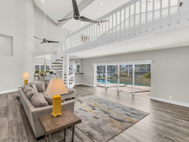 living room featuring ceiling fan, wood-type flooring, and a high ceiling